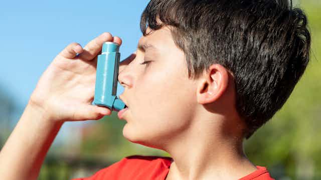 A boy with asthma uses an inhaler.
