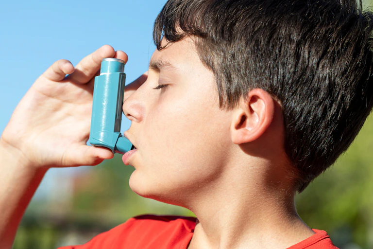 A boy with asthma uses an inhaler.
