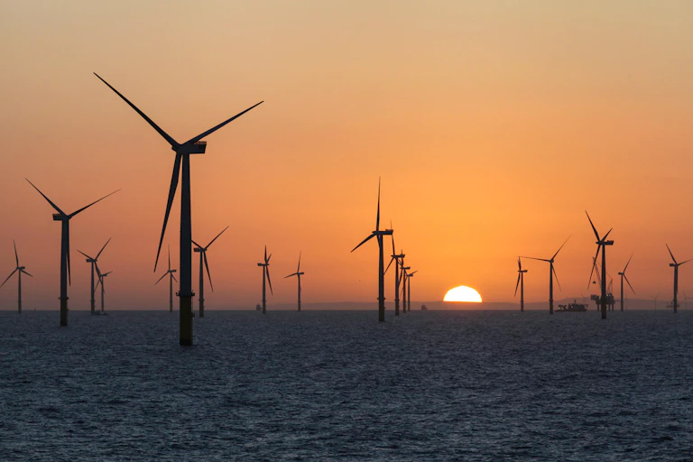 An offshore windfarm at sunrise.