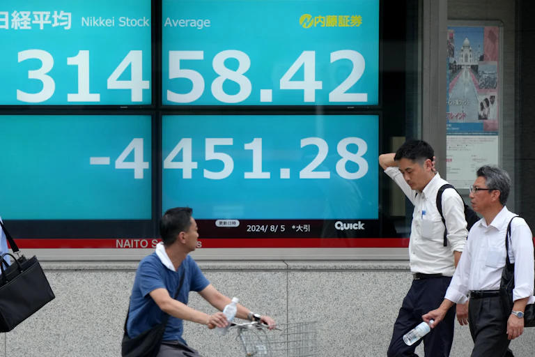 Pedestrians walk past a display showing the closing information of the Tokyo stock exchange.