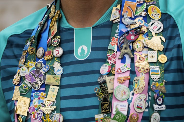 Olympic pins are seen on a shirt worn by a volunteer at the Paris Olympics.