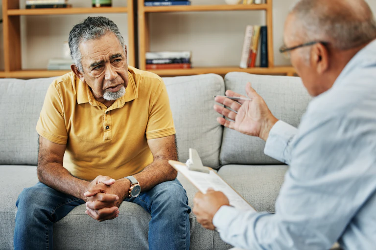A senior man talking to a doctor or therapist.