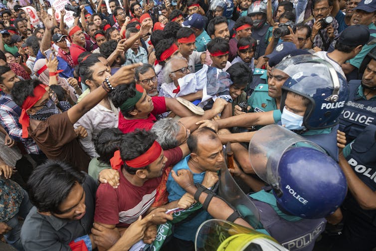 A crowd of mostly men clash with police in riot gear.