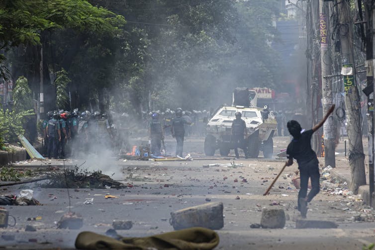 A young man clashes with police on a deserted, smoky street.