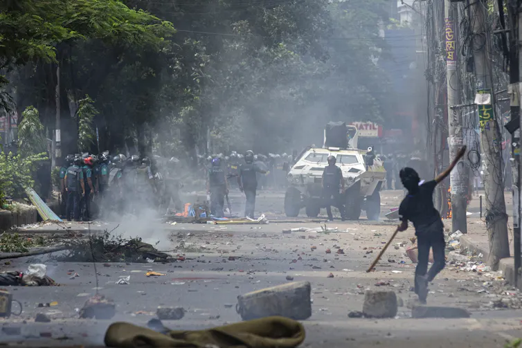 A young man clashes with police on a deserted, smoky street.
