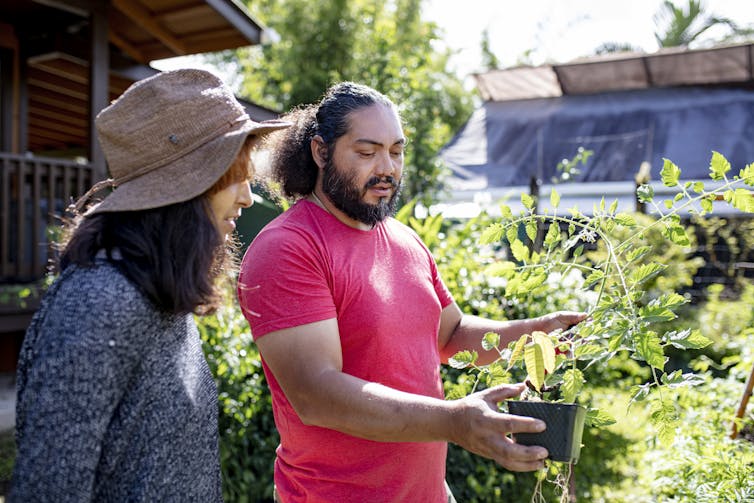 woman and man talking about a potted plant in garden