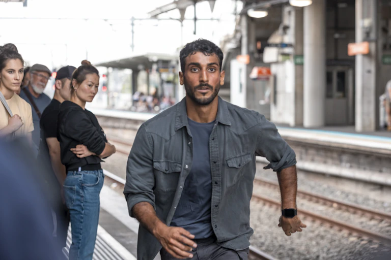 A man of runs on a train station platform.