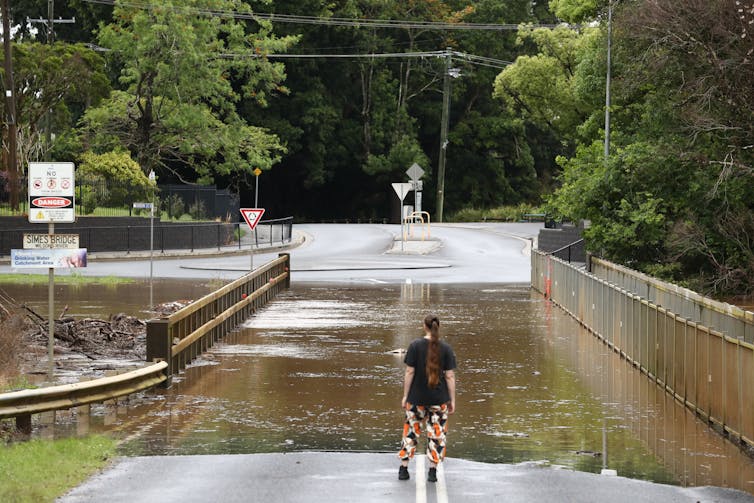 Woman stands on flooded road