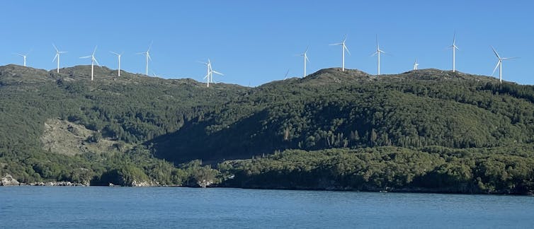 Wind turbines along a ridge next to the sea