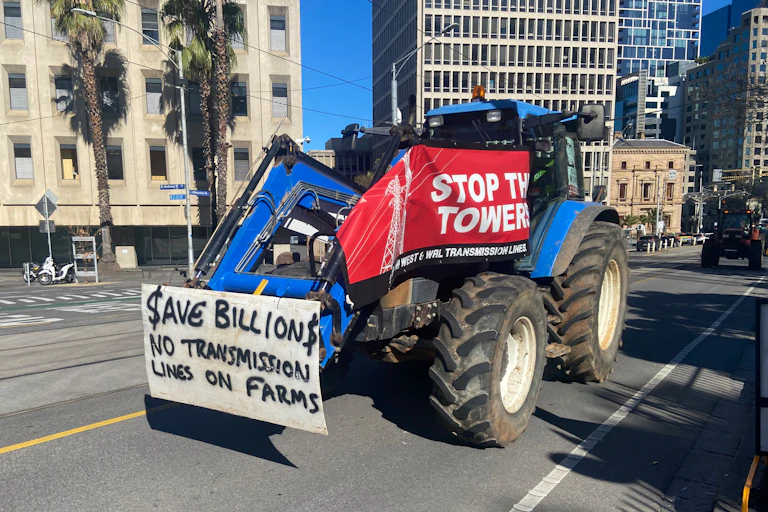 A protester against transmission lines on farms drives a tractor through a city