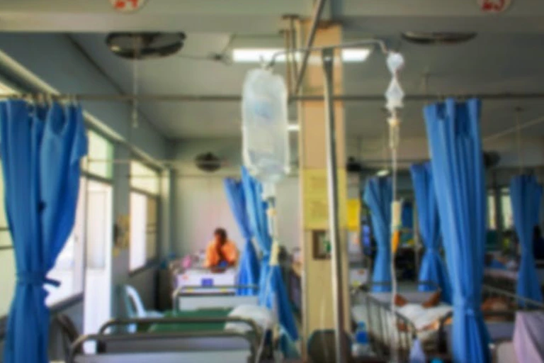 Une chambre d'hôpital avec des rideaux tirés et une perfusion.