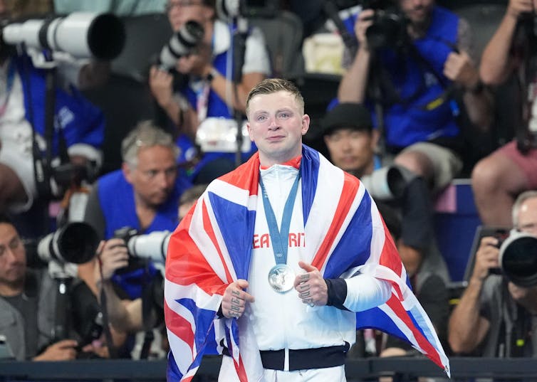 A British Olympic athlete draped in the Union Jack celebrating his silver medal.