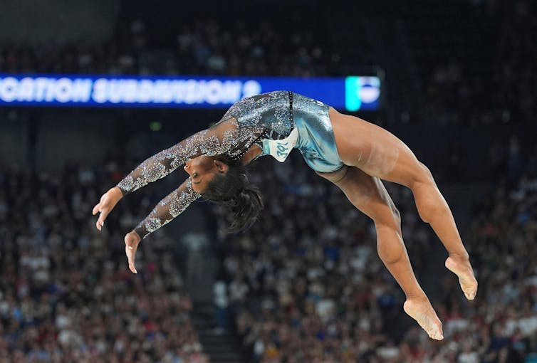 A ginasta americana Simone Biles faz um mortal para trás na trave nas Olimpíadas de Paris 2024.