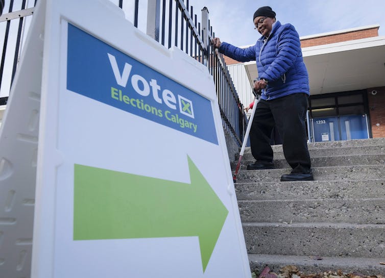 A voter carrying a can walks down a flight of stairs with a Vote sign at the bottom of the concrete staircase.