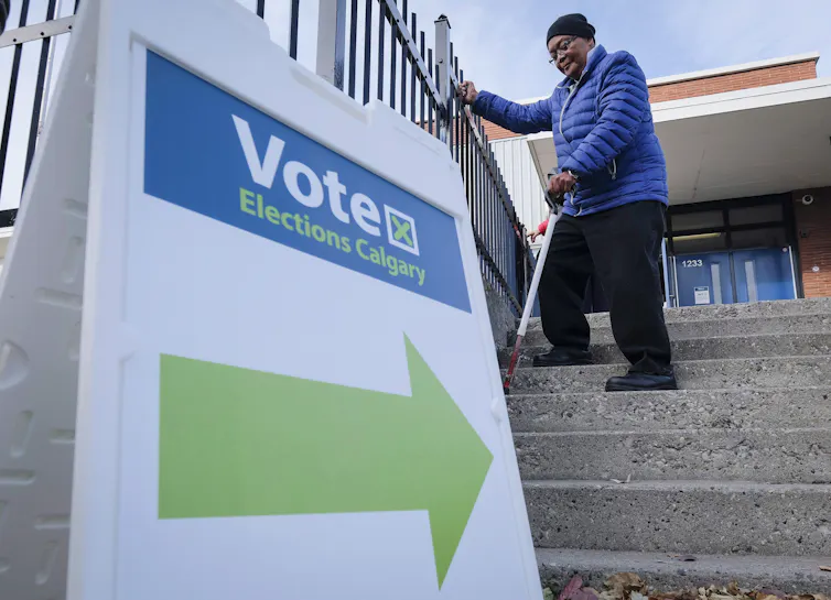 A voter carrying a can walks down a flight of stairs with a Vote sign at the bottom of the concrete staircase.