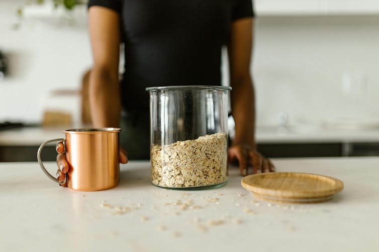 Person holds cut next to oat jar.
