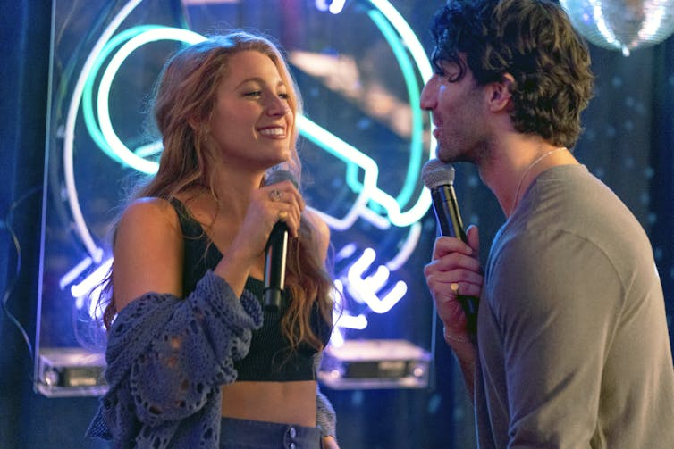Film still: Lily and Ryle sing Karaoke.