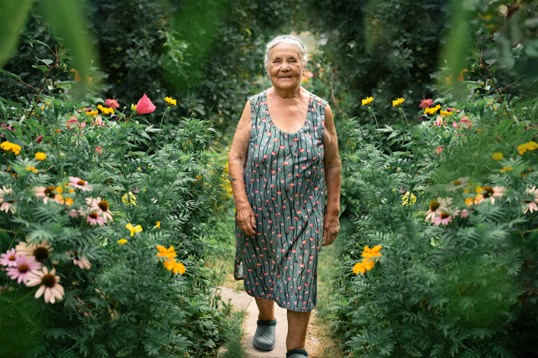 An old woman walking in a garden.
