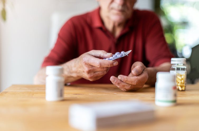 A man with a number of medications on a table.