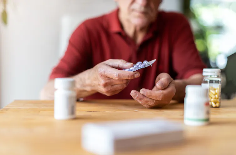 A man with a number of medications on a table.
