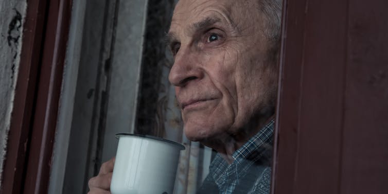 older man looks into distance holding mug