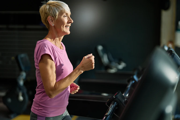 An older woman runs on a treadmill.