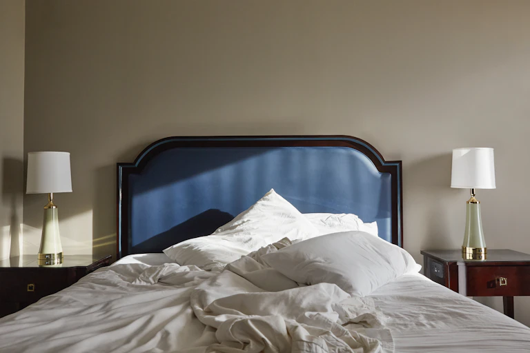 a messy bed with a blue headboard