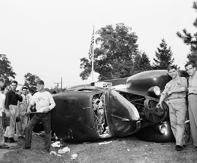 Demonstrators overturn a car.