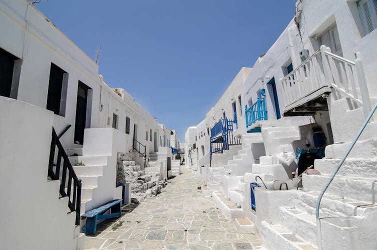 Looking down a stone street of white homes with steps.