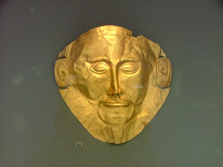 A gold mask depicting a bearded man.