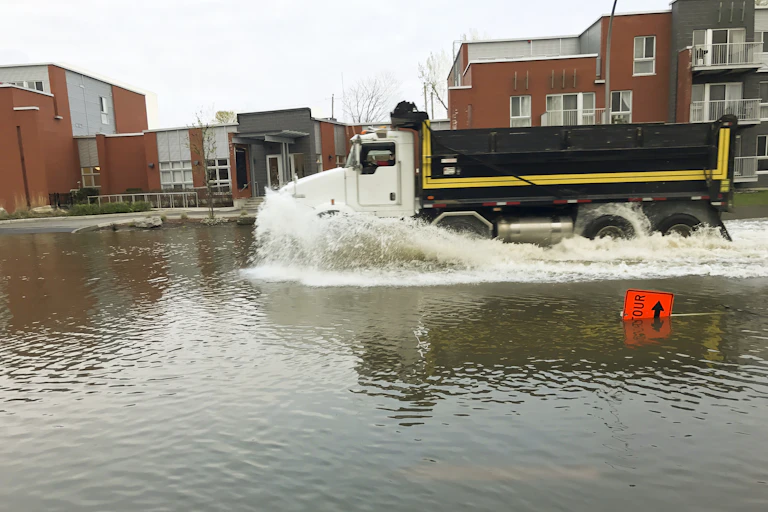 a truck drives through a flooded city street