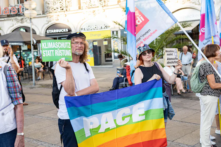 An anti-war protester carries a flag saying Pace (peace)