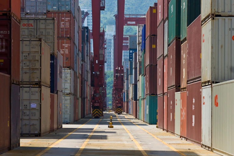 Tall rows of shipping containers at a dock in Hong Kong.