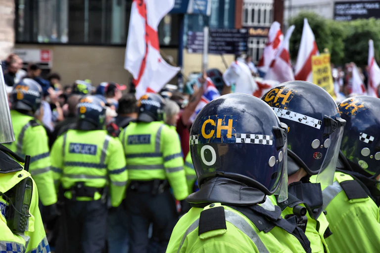 UK riot police surround people holding England flags.