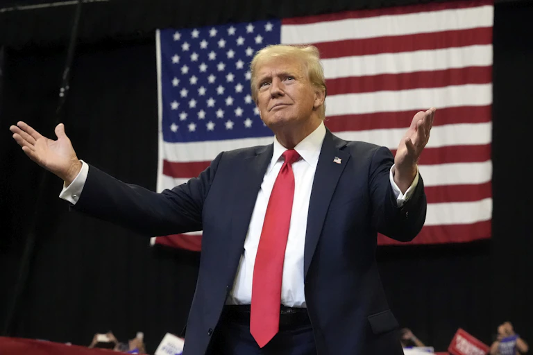 Un homme âgé (Donald Trump) se tient devant le drapeau des États-Unis