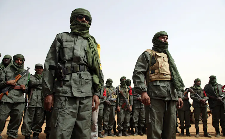 Armed soldiers stand in a desert.