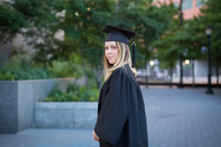 Young woman in cap and gown looking at camera