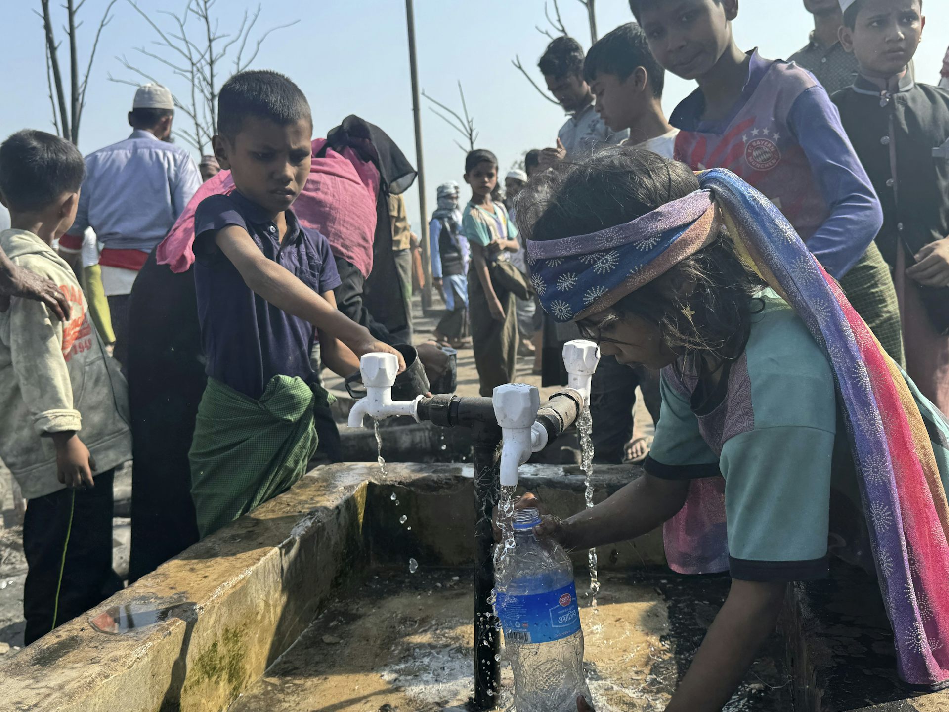 Los niños recogen agua potable en botellas de agua vacías.