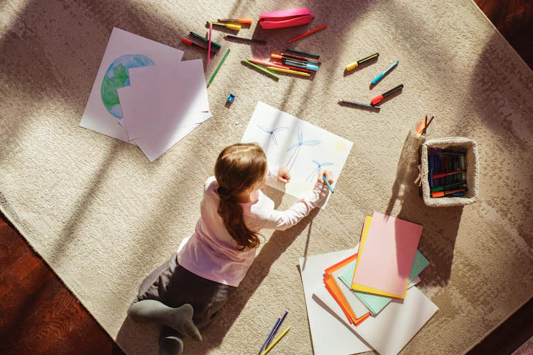 Photo from above of girl drawing wind turbines.