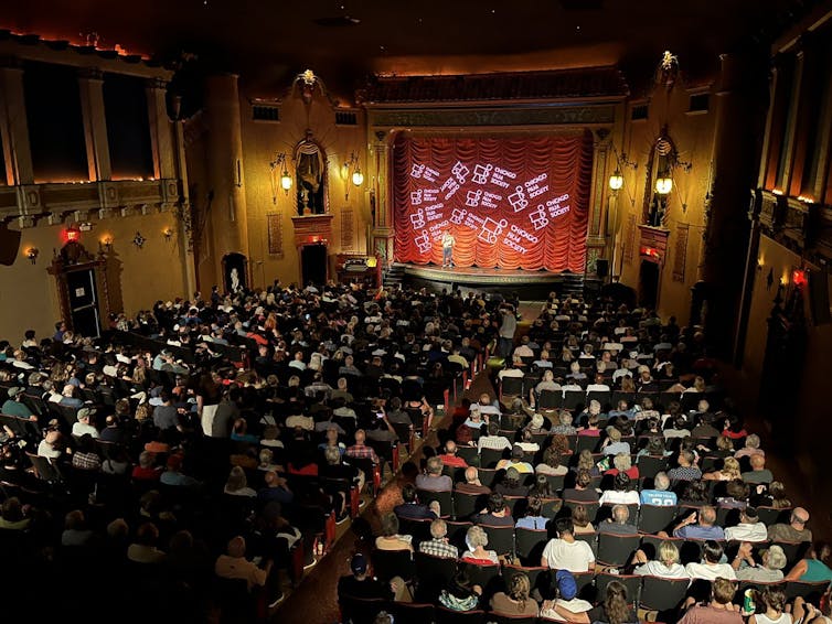 A packed audience at an old-fashioned movie theater.