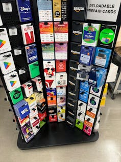Rack of brightly colored gift cards with sign in top right: reloadable download cards