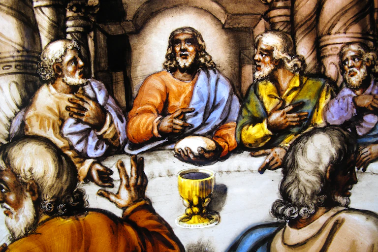 Uma pintura que mostra várias pessoas em uma mesa olhando para um homem no centro. Sobre a mesa há uma xícara dourada.