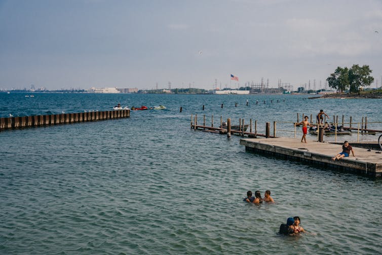 Kids swim in Lake Michigan with factories in the background.