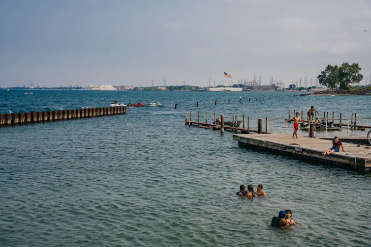 Kids swim in Lake Michigan with factories in the background.