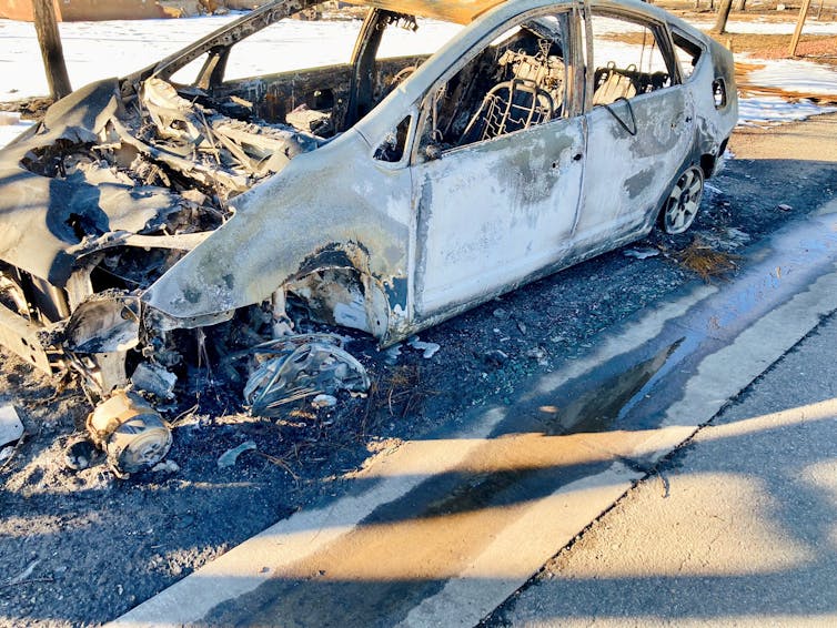 A burned out car on the side of the road.