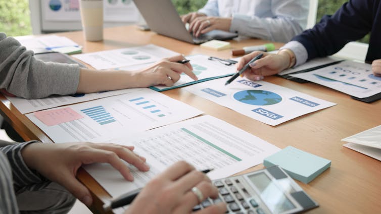 Closeup of company report pages on a table, businesspeople discussing