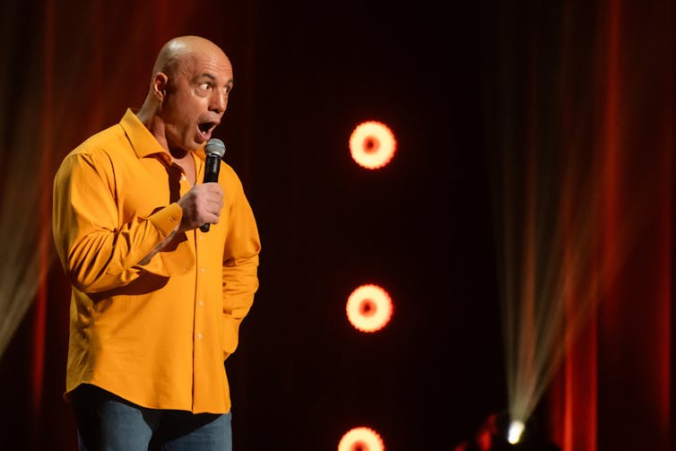 Joe Rogan on stage in a theatre.