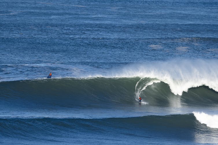 A large wave, with a small surfer.