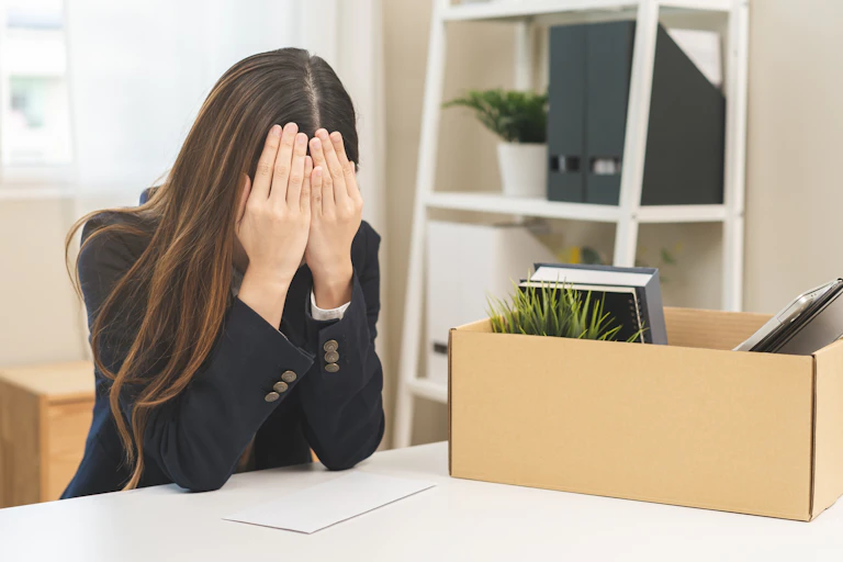 Woman sitting at desk holding her head in her hands