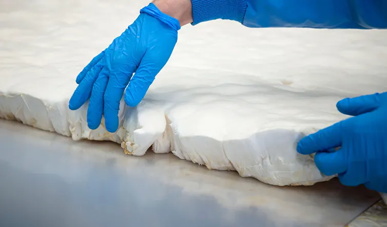 Unas manos con guantes azules sujetan un material blanco.